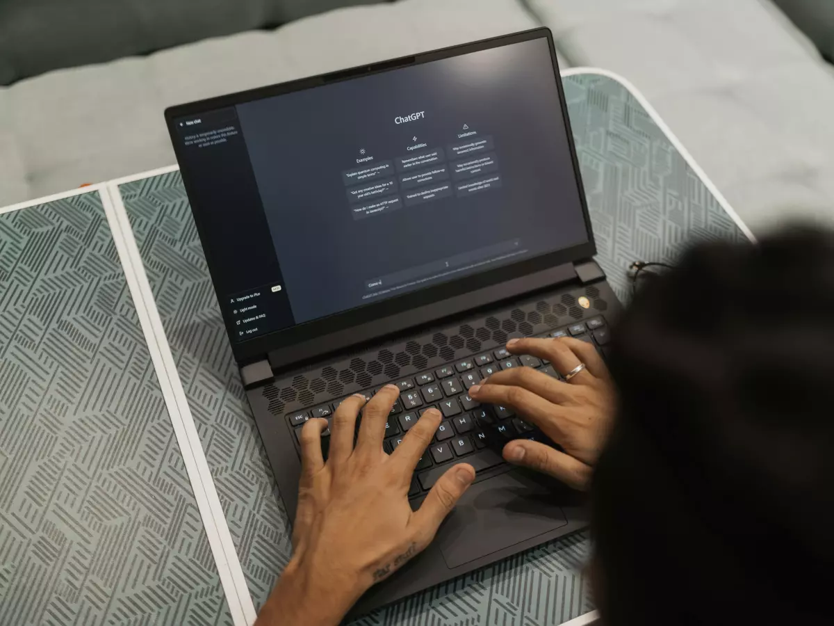 A person working on a laptop, with the screen showing a glimpse of a document or webpage.